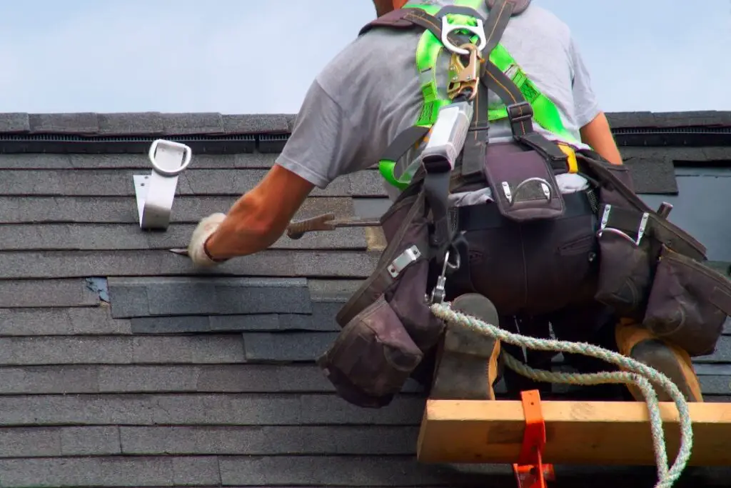 a roofer fixing shingles on a roof