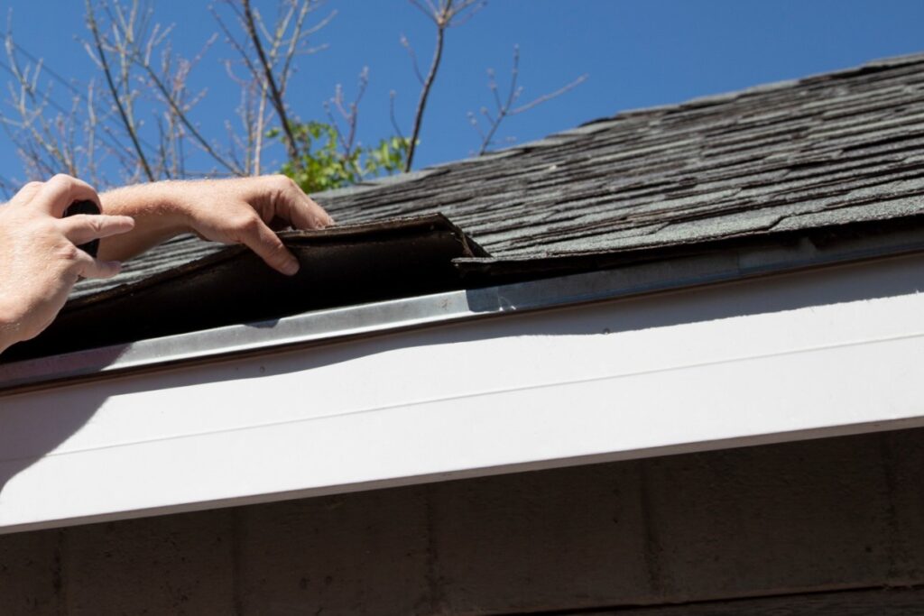 Roof heat damage - A man checking a home's asphalt shingle roofing.