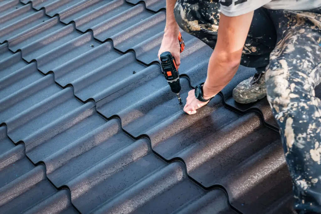 Metal roofing installation - A male contractor using special tools to install a metal roof.