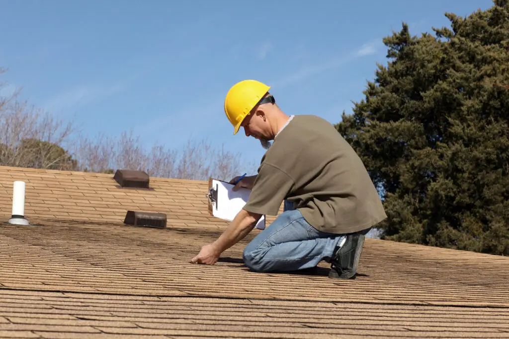 Inspection for roof heat damage - A male roofing contractor conducting a residential roofing inspection.