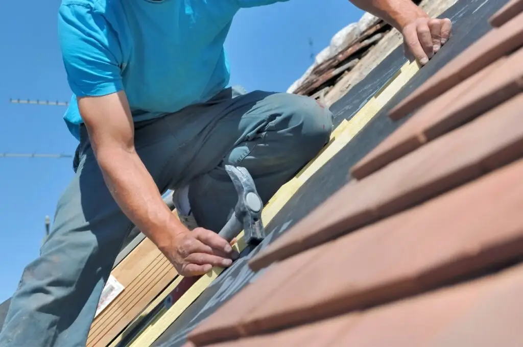 Choosing roof materials - A male contractor replacing a home's roof.