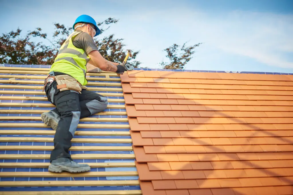 Deciding on roof materials - A male contractor installing clay tile roofing on a residential property.