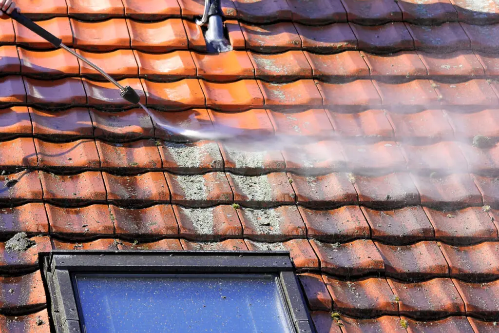 Clearing mold and algae on roofs - A roofing contractor washing a home's roof with fungicide.