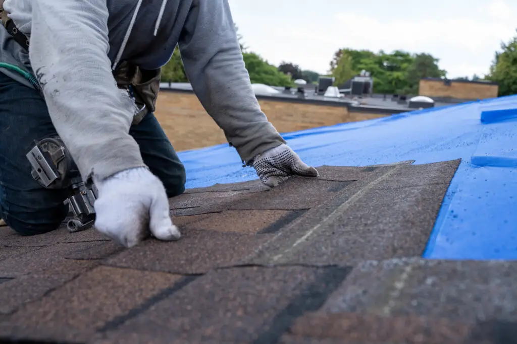 Repairing roof problems - A male contractor installing a new residential roof.