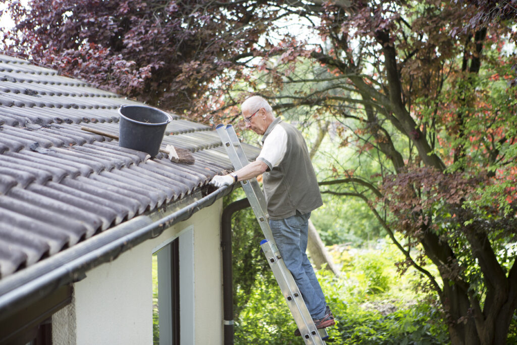 A senior man doing DIY roof repair at their home.