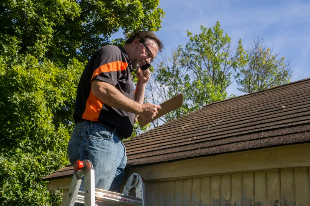 Qualifying for homeowner's insurance - A male roofing contractor calling an insurance company regarding roof repairs.