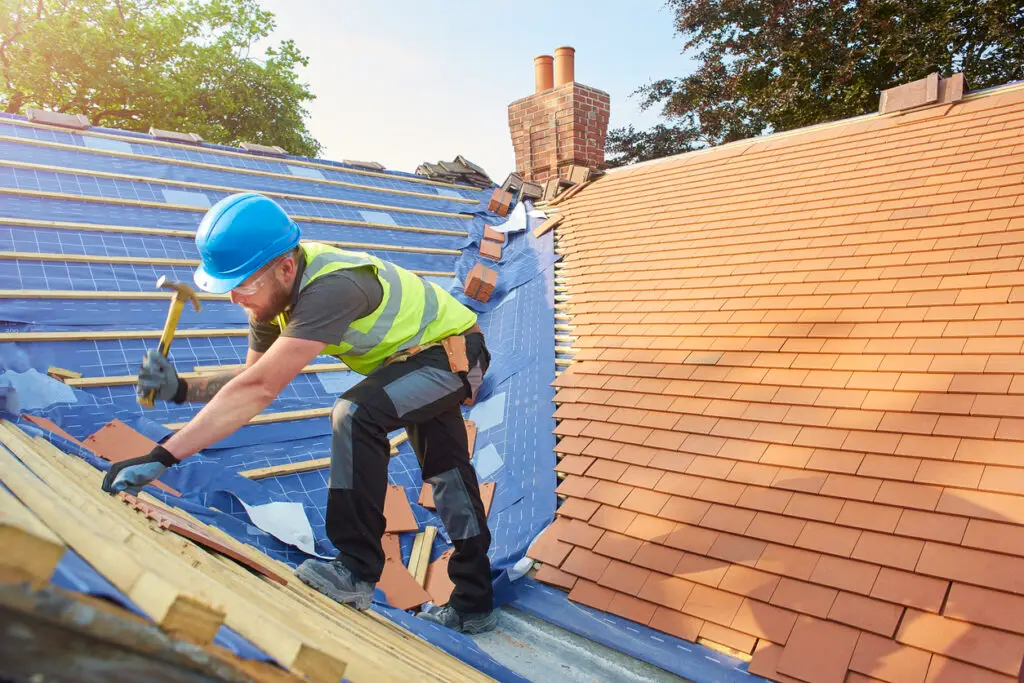 Roof replacement process - A male roofing contractor starting a residential property's roof replacement process.