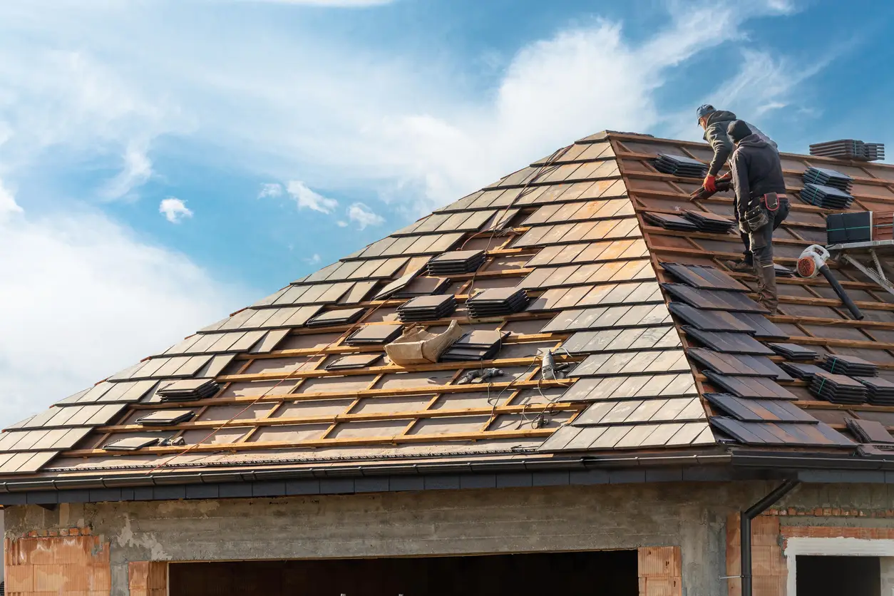 Scheduling roof replacement - A male contractor installing a new roof on a residential property.