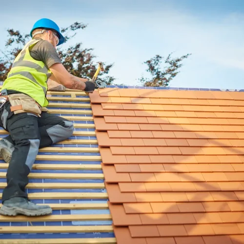 Deciding on roof materials - A male contractor installing clay tile roofing on a residential property.