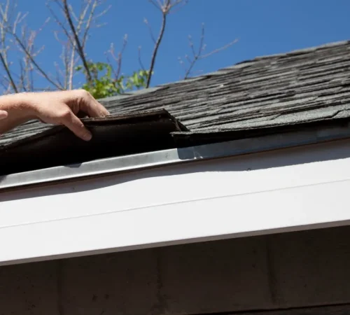 Roof heat damage - A man checking a home's asphalt shingle roofing.