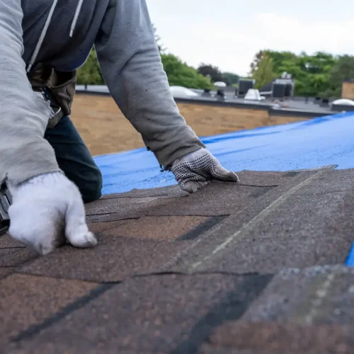 Repairing roof problems - A male contractor installing a new residential roof.